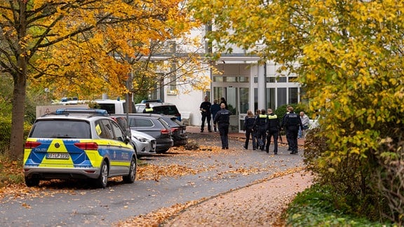 Polizeiaustos und Polizisten vor einer Klinik in Bad Berka.