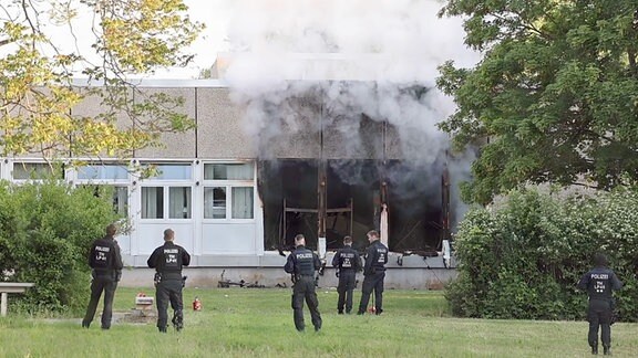 Polizeikräfte vor einem rauchenden Gebäude