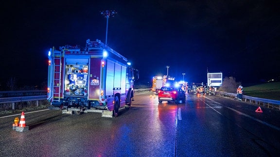 Polizei- und Feuerwehrfahrzeuge stehen nach einem Unfall auf einer Autobahn.