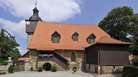 Eine Kirche von der Seite mit kleinem Holzturm.