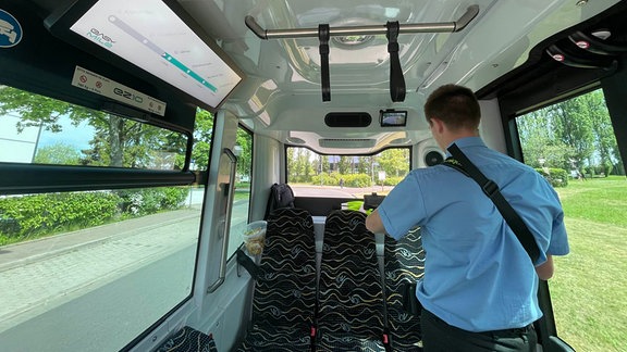 Ein Mann steht im Innenraum eines autonom fahrenden Busses.
