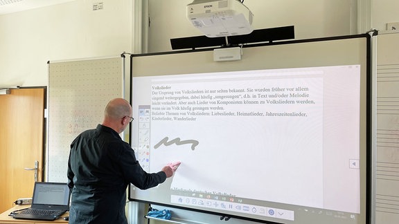 Thomas Umbreit schreibt an eine digitale Tafel.