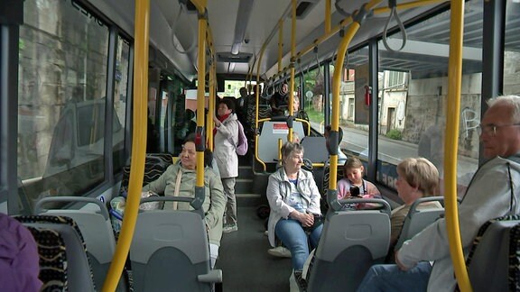 Fahrgäste verschiedenen Alters sitzen in einem fahrenden Bus