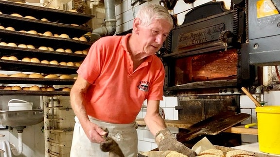 Bäcker Wigbert Weißleder holt Brote aus einem Ofen