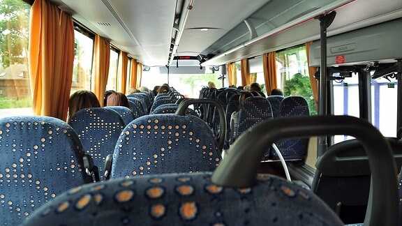 Das Innere eines Busses. Die Sitze und die Hinterköpfe der Fahrgäste sind zu sehen