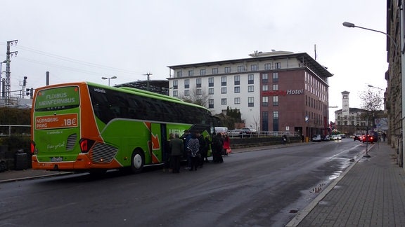 Fahrgäste laden Gepäck in einen Fernbus, der an der Erfurter Fernbus-Haltestelle in der Kurt-Schumacher-Straße steht