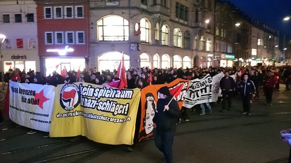 Straßenfüllende Menschenmenge hinter Transparenten wie "Offene Grenzen für alle" oder "Kein Spielraum für Nazischläger"