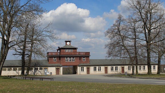 Das Hauptgebäude auf dem Gelände der Gedenkstätte Buchenwald: ein langgestreckter Flachbau mit einer Turmuhr in der Mitte.