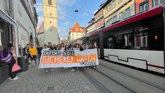 "Erfurt soll sicherer Hafen werden" steht auf einem von Demonstrierenden getragenen Transparent.