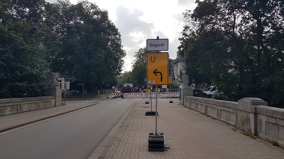 Umleitungsschild steht am Straßenrand. Im Hintergrund ist eine Baustelle zu sehen.