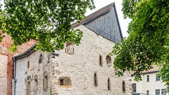 Die Alte Synagoge in Erfurt: Ein Haus mit spitzem Dach und einer hellen Fassade, an der noch einzelne Steine erkennbar sind.