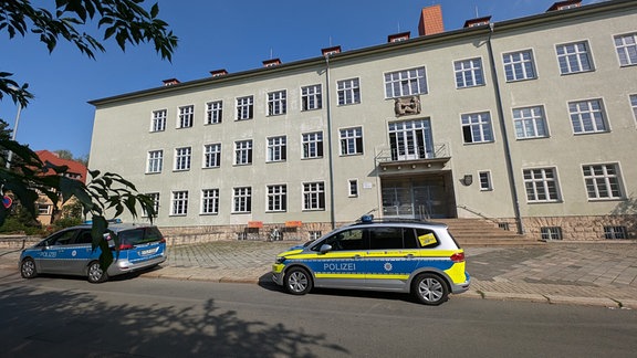 Zwei Polizeiautos stehen auf der Straße vor dem Heinrich-Mann-Gymnasium in Erfurt.