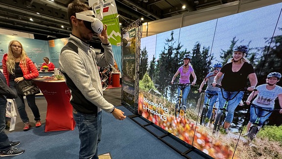 Ein Mann trägt auf einer Messe eine VR-Brille 