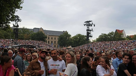 Viele Menschen stehen und sitzen auf den Tribühnen am Erfurter Domplatz.