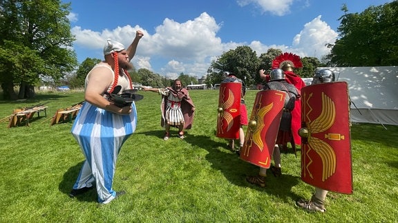Ein Mann als Obelix verkleidet kämpft gegen römische Soldaten.