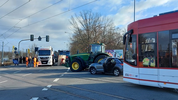 Eine Straßenbahn fährt an einer Demo mit Traktor, Lkw und Auto vorbei.