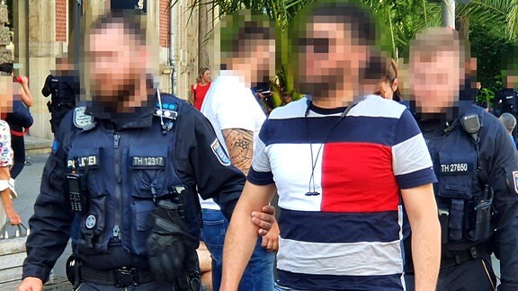 Ein Polizist führt einen festgenommenen Mann auf dem Erfurter Anger