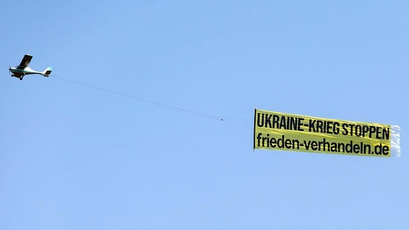 Ein Flugzeug zieht einen Schleppbanner mit der Aufschrift UKRAINE KRIEG STOPPEN FRIEDEN-VERHANDELN.DE und fliegt dabei über dem Bonner Raum samt dem Siebengebirge. 