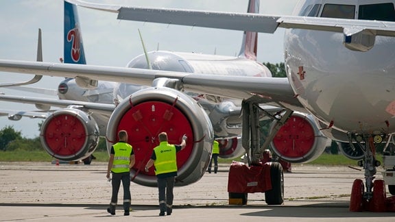 Flughafenmitarbeiter laufen zwischen geparkten Flugzeugen