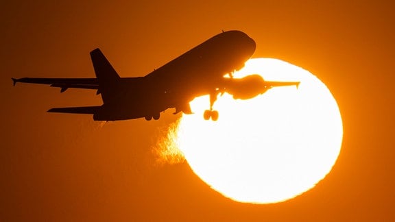 Ein Flugzeug hebt vor der untergehenden Sonne ab