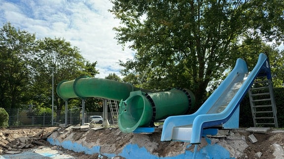 Zwei Wasserrutschen stehen neben einem zerstörten Schwimmbecken.