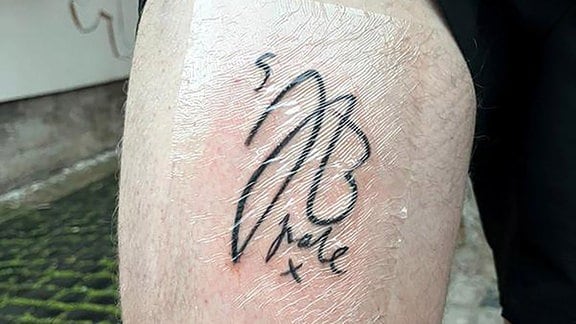 Ein Fußballfan zeigt das Autogramm von Fußballstar Jude Bellingham als Tattoo auf seinem Oberschenkel.