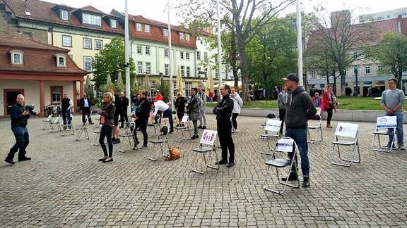 Gastronomen aus Thüringen stehen vor der Staatskanzlei in Erfurt neben leeren Stühlen
