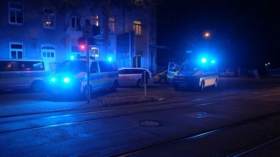 Mehrere Polizeiwagen blockieren eine Straße.