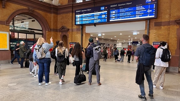 Bahnreisende stehen vor der Anzeigetafel im Erfurter Hauptbahnhof