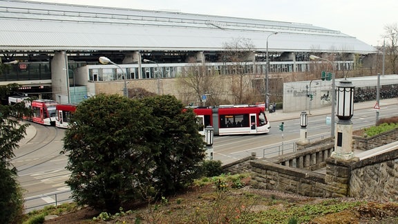 Blick auf den Hauptbahnhof in Erfurt vom Stadtpark aus, eine Straßenbahn ist auf den Schienen unterwegs.