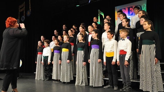 Serbischer Kinder- und Jugendchor singt auf einer Bühne.