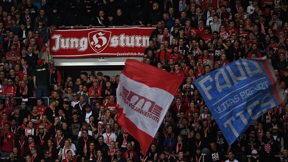 Ein Banner mit der Aufschrift "Jung-Sturm" hängt in einem Stadion zwischen Zuschauern.