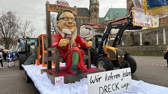 Ein Karnevalswagen auf dem Domplatz, mit einer großen Figur abgebildet.