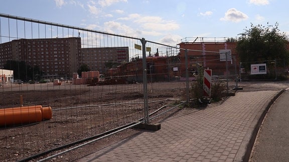 Abgesperrte Baufläche am Roten Berg mit Plattenbauten dahinter