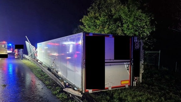 Ein Sattelzug liegt in der Nacht umgekippt auf dem Grünstreifen einer Autobahn.