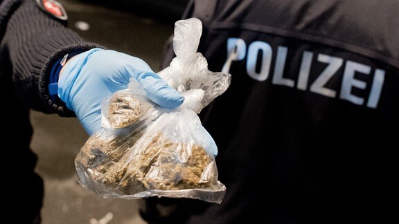 Eine Polizistin zeigt einen Beutel mit sichergestellten Marihuana