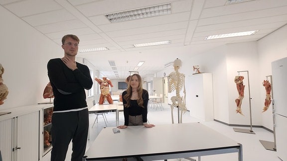 Ein Mann und eine Frau in einem Raum mit Modellen des menschlichen Körpers.