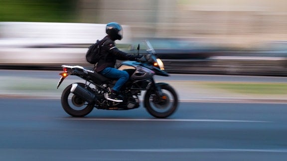 Ein Mann fährt auf einem Motorrad über eine Hauptstraße.