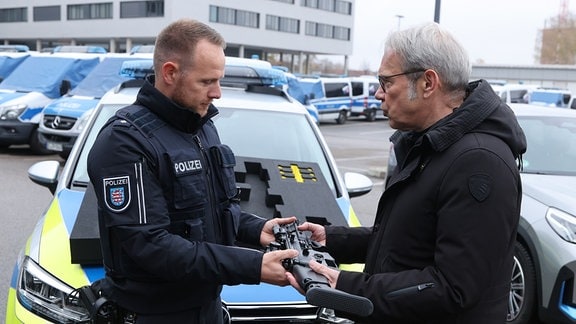 Georg Maier (r, SPD), Innenminister von Thüringen, übergibt an Polizeioberkommissar Alexander Albinus eine neue Mitteldistanzwaffe der Thüringer Polizei, bei einer Pressekonferenz des Landeskriminalamts. 