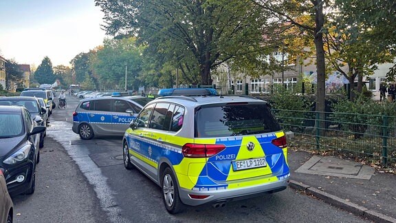 Zwei Polizeiautos stehen in der Straße vor einer Schule in Erfurt