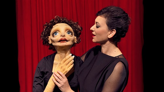 Puppentheaterspielerin mit einer Handpuppe, die an Edith Piaf erinnert