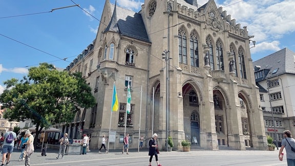 Menschen laufen vor dem Rathausgebäude in Erfurt