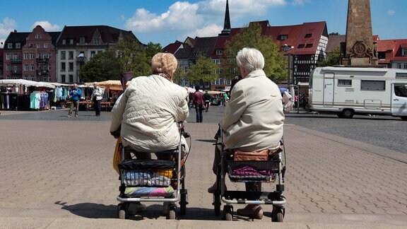 zwei alte Frauen sitzen in ihren Rollatoren und unterhalten sich auf dem Domplatz in Erfurt, Thüringen
