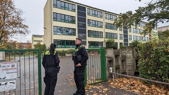 Zwei Polizisten stehen vor einer Schule in Erfurt.