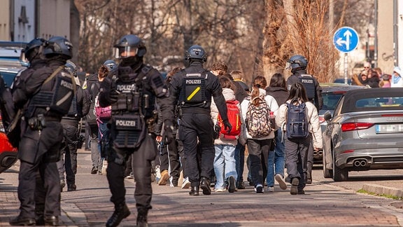 Polizisten begleiten Kinder aus einem Schulgebäude