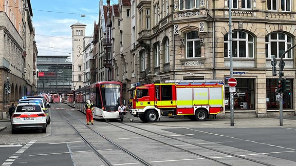 Notarzt- und Feuerwehrwagen stehen neben einer Straßenbahn in der Erfurter Bahnhofsstraße