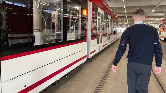 Ein Mann läuft neben einer Straßenbahn in einem Depot.