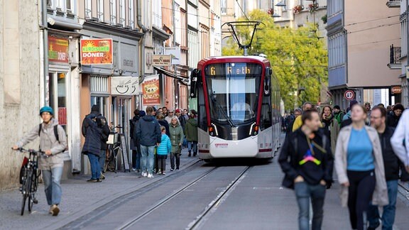 Eine Straßenbahn in der Erfurter Innenstadt, Fußgänger auf Gehwegen