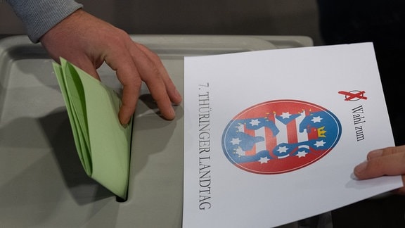 Ein Wähler wirft bei der Stimmabgabe zur Landtagswahl in Thüringen seinen Wahlzettel in einem Wahllokal in eine Wahlurne.