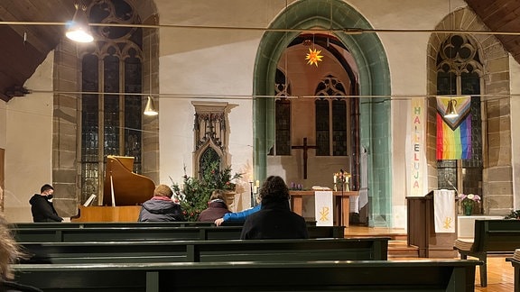 Menschen sitzen auf Bänken in einem Kirchenschiff